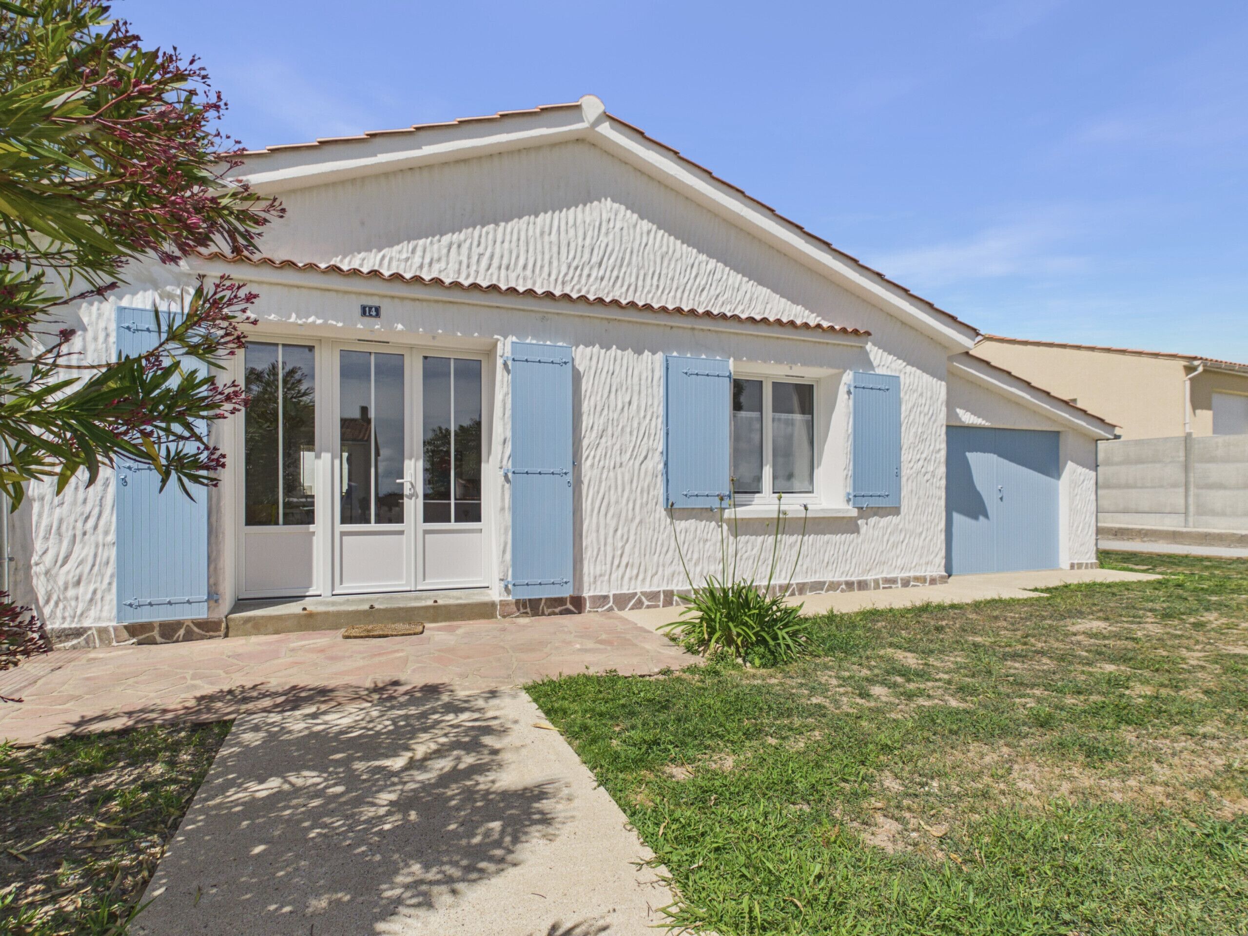 A single-story house with a white exterior, blue shutters, and a tiled roof.