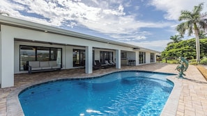 A modern house with a swimming pool, outdoor seating, and a view of the sky. - Stunning five-bedroom, 3 full bathroom home with views of lake and golf course (Marco Island)
