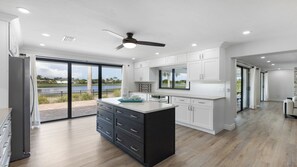 A modern kitchen with a large island, white cabinetry, and a view of a lake. - Stunning five-bedroom, 3 full bathroom home (Marco Island)