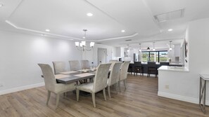 A modern dining area with a rectangular table, six upholstered chairs, and pendant lighting. - Stunning five-bedroom, 3 full bathroom home (Marco Island)