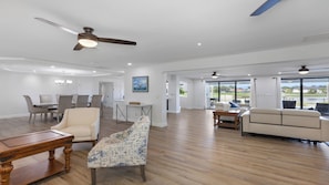 A spacious living area with a dining set, a sofa, a patterned bench, and a ceiling fan. - Stunning five-bedroom, 3 full bathroom home with views of lake and golf course (Marco Island)