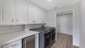 A kitchen with white cabinets, a stainless steel dishwasher, and a built-in oven. - Stunning five-bedroom, 3 full bathroom home with views of lake and golf course (Marco Island)