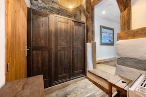 A rustic interior with wooden doors, stone walls, and a wooden bench. - Chalet Le Hameau Tranquille (Courchevel)
