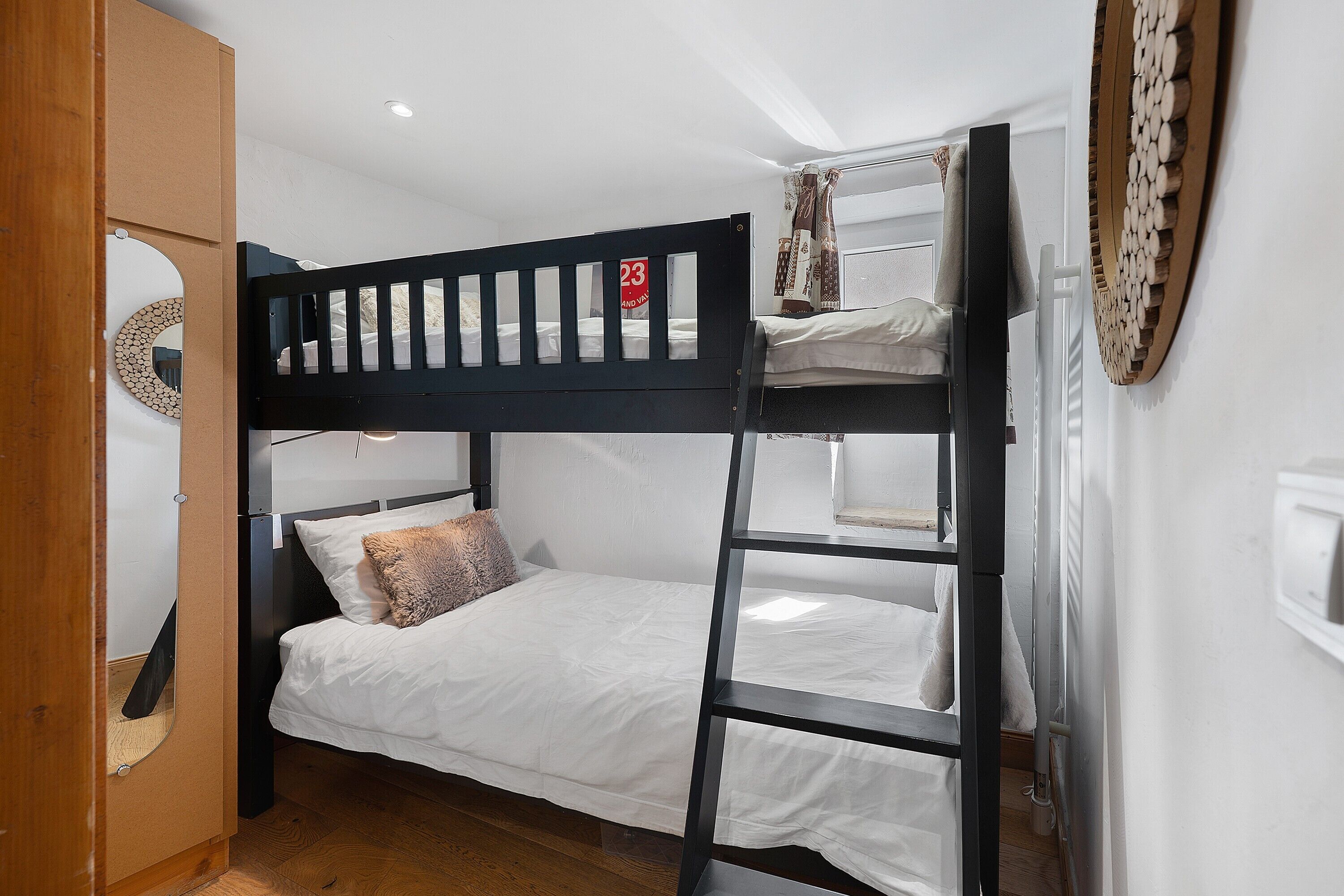 Un lit superposé avec une tête de lit, un miroir et un élément décoratif fixé au mur.