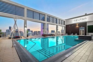 Piscina no terraço com vista para a cidade, área coberta com assentos e um edifício com a inscrição 'CENTRO'.