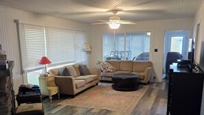 A spacious living room with a wooden floor, a sofa, a coffee table, and a TV. - Lake front cottage with private dock
4 Bedroom  2 bathroom (Innisfil)