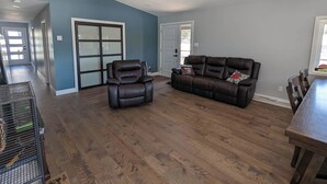 Una sala de estar con un sofá de cuero marrón, un sillón reclinable y una mesa de comedor.