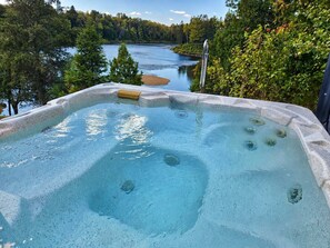 Un bain à remous avec vue sur un lac et une forêt.