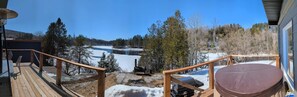 Une terrasse avec vue sur un lac, entourée d’arbres et donnant sur un bâtiment doté d’une cheminée.