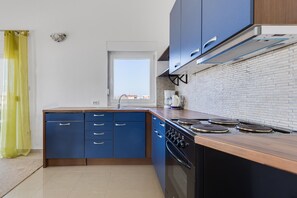 A modern kitchen with blue cabinets, a stove, and a window. - Kotari Sukošan in Sukošan - Nord-Dalmatien / Kotari Sukošan in Sukošan - Appartement für 4 Personen AP3 (Sukosan)
