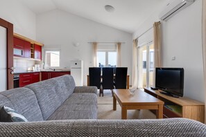 Ein kompakter Wohnbereich mit Küchenzeile, einer Couch, einem Esstisch und einem Fernseher.
