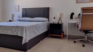 Ein Schlafzimmer mit Bett, Nachttischen, einem Schreibtisch und einem Bürostuhl.