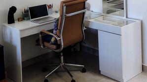 Ein moderner Arbeitsbereich mit Schreibtisch, Stuhl, Laptop und einer Pendelleuchte.