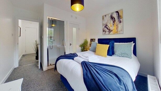 A hotel room with a bed, a shower, a door, and a painting on the wall. - Cosy 1 Bedroom Flat Near Balham Station (London)