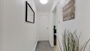A hallway with a white door, a black-framed mirror, and wooden wall decorations with motivational phrases. - Cosy 1 Bedroom Flat Near Balham Station (London)