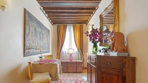 Ein Zimmer mit Holzboden, einem Tisch mit weißen Tischdecken, einem Stuhl, einem Holzschrank und einem großen Spiegel.