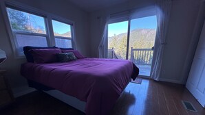 Ein Schlafzimmer mit Bett, einem Fenster und Blick auf eine Terrasse.