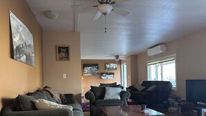 Ein Wohnzimmer mit zwei Sofas, einem Holztisch, einem Deckenventilator und einem Fernseher.