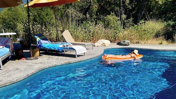 Ein Swimmingpool mit Liegestühlen und einer Person, die auf einem Luftbett liegt.