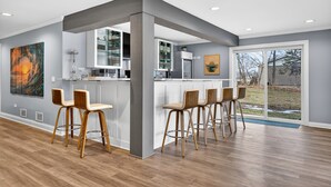 Een moderne keuken met een bar, houten barkrukken en een groot raam.