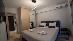 Une chambre à coucher moderne, comprenant un lit, une table de chevet, un miroir et un luminaire fixé au plafond.