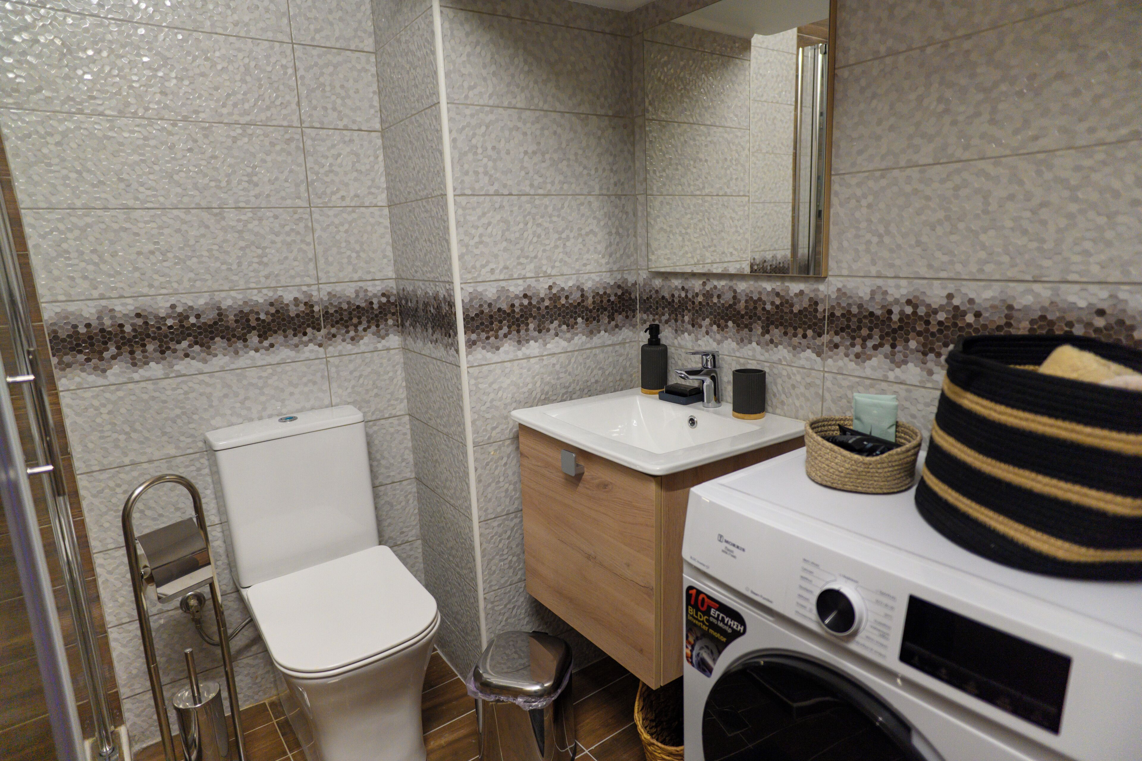 Ein Badezimmer mit Toilette, Waschbecken, Spiegel und Waschmaschine.