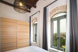 A bedroom with a bed, a window with curtains, a wooden headboard, and a balcony view. - Vineyard View, next to Best Wineries, "Theros" appartment (52QJ+W6 Avgeniki)