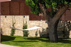 A hammock tied between a tree and a stone wall, with a grassy area in front. - Vineyard View, next to Best Wineries, "Theros" appartment (52QJ+W6 Avgeniki)