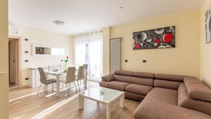 Ein modernes Wohnzimmer mit einem braunen Sofa, einem Esstisch mit Stühlen und einem Couchtisch.
