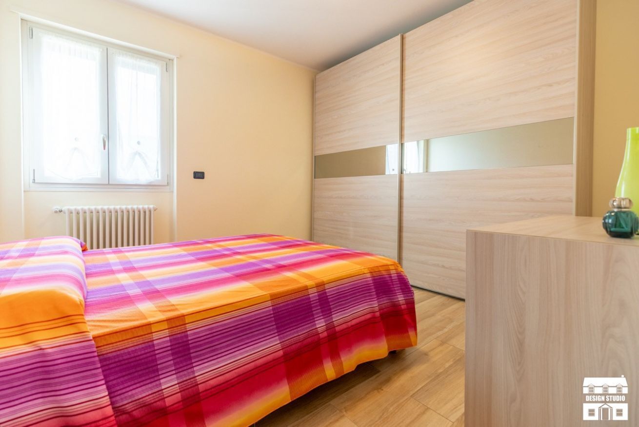 Ein Schlafzimmer mit Bett, Heizkörper, Fenster und Kleiderschrank.