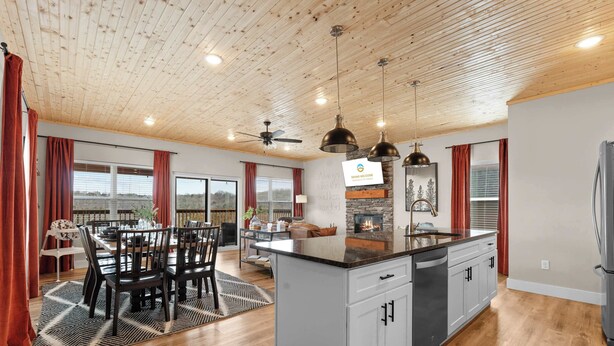 Una cocina amplia con una isla central, techo de madera y ventanas grandes.