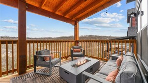 Una terraza cubierta al aire libre con un hogar para fuego, zona de estar y vistas del paisaje.