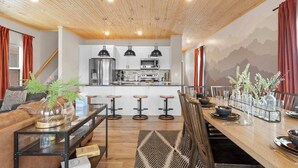 Una cocina moderna con armarios blancos, electrodomésticos de acero inoxidable y techo de madera.