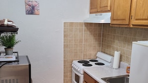 Una cocina con armarios de madera, estufa, lavaplatos y una pequeña mesa con una planta.