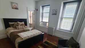 Un dormitorio con cama, radiador y ventana con persianas.
