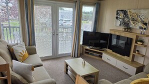 Een woonkamer met een bank, salontafel, televisie en open haard.