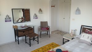 Une chambre à coucher comprenant un lit, un bureau, une chaise, un miroir, une armoire et une petite table.