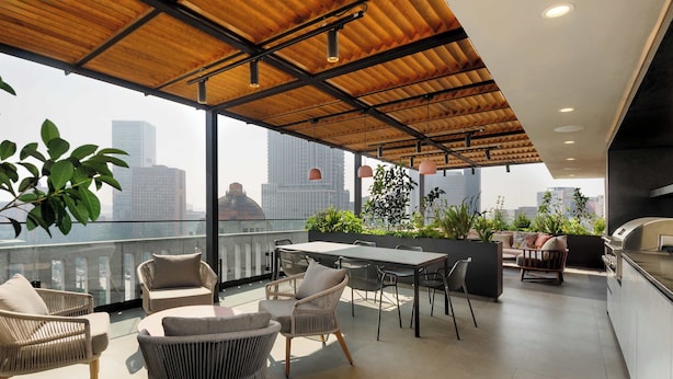 A rooftop terrace with wicker furniture, a dining table, and a kitchen area. - w* | Tasteful 1BR w/ Private Balcony in Tabacalera (Ciudad de México)