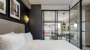 A modern hotel room with a large bed, a dining area with a table and chairs, and a view through a glass door. - w* | Tasteful 1BR w/ Private Balcony in Tabacalera (Ciudad de México)