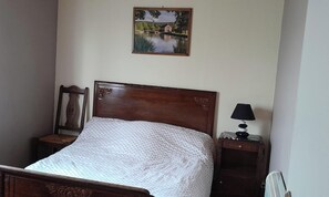 A bed with a wooden headboard, a bedside table with a lamp, and a painting on the wall. - La crapaudiere (Charrin)