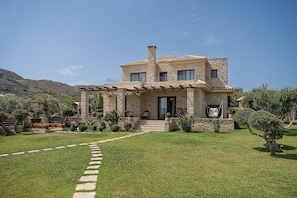 A two-story stone house with a covered patio, a stone chimney, and a well-maintained lawn. - Chania Villa for 7 Near the sea (Kissamos)