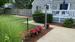 Un jardin résidentiel avec un chemin, une clôture et une maison dotée d’un porche.