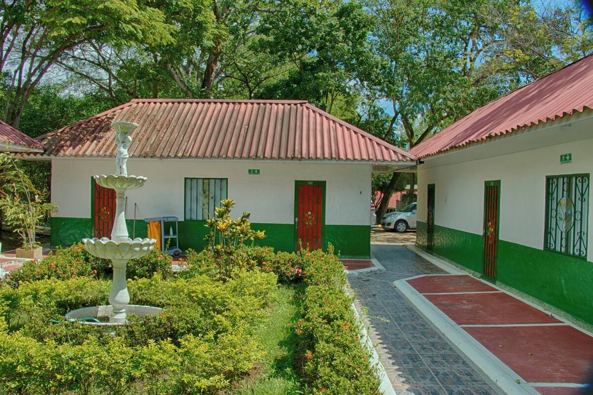 Um edifício com telhado de azulejos, uma fonte e um caminho que leva à entrada.