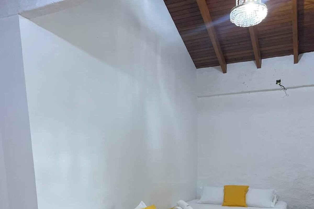 Quarto de hotel com três camas, cada uma com um cobertor amarelo e almofadas brancas.