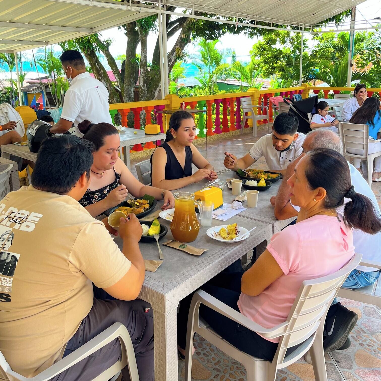 Un groupe de personnes est assis à une table dans un restaurant en plein air, où se trouvent également des chaises.