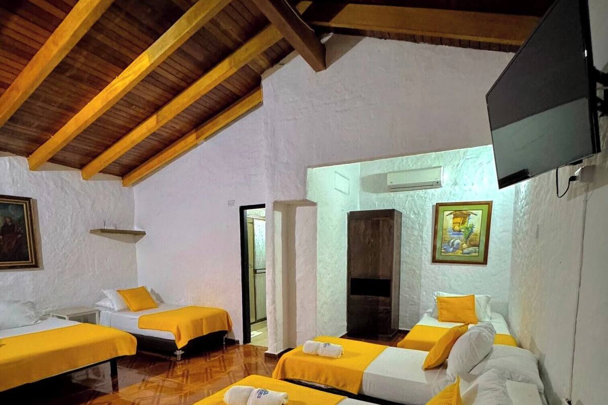 Quarto de hotel com duas camas, televisão e teto de madeira.