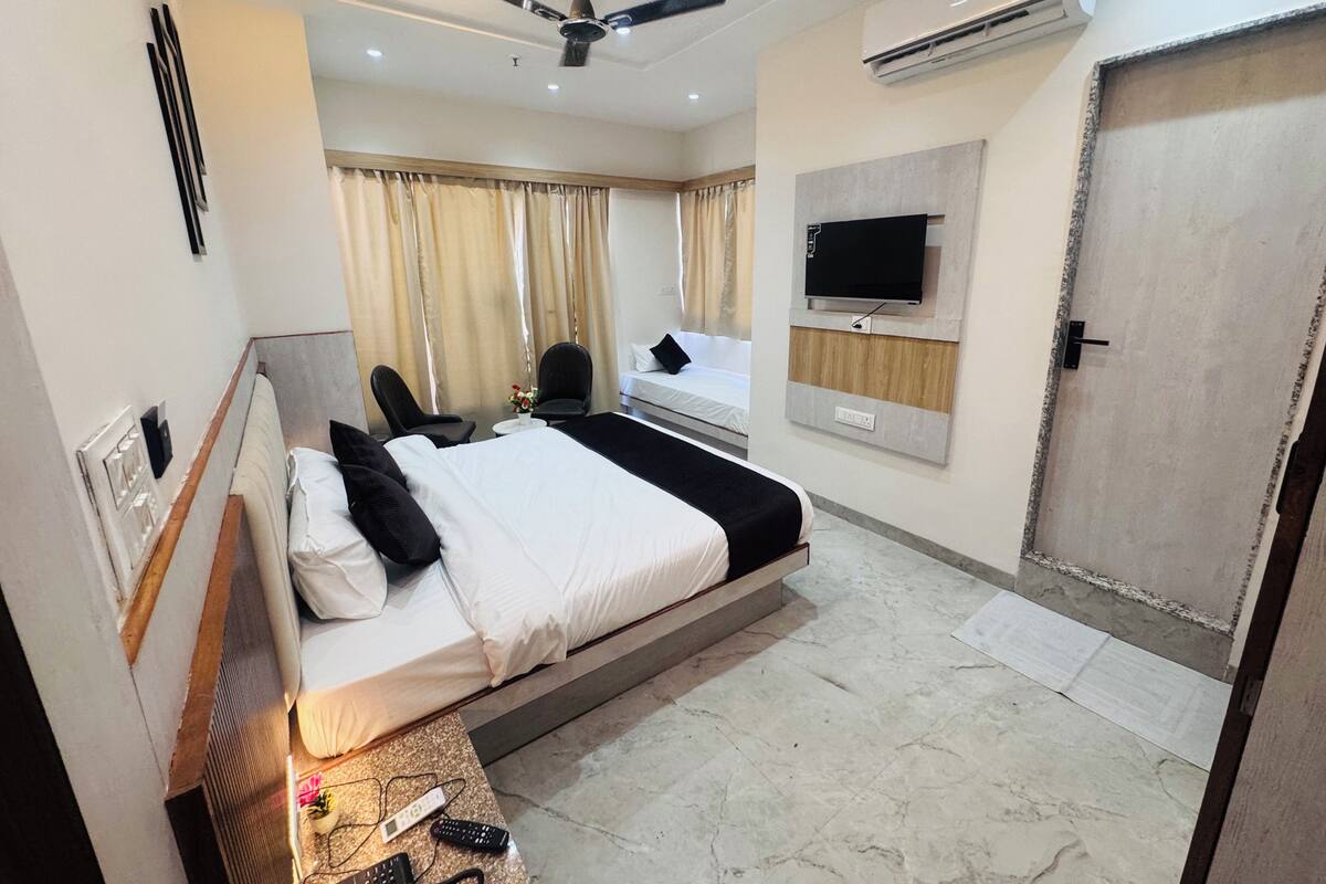 Una habitación de hotel con cama, televisión, ventilador de techo y aire acondicionado, además de una puerta.