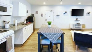 Une cuisine moderne avec des meubles blancs, un four à micro-ondes, une cuisinière et un coin repas comprenant une table et des chaises.