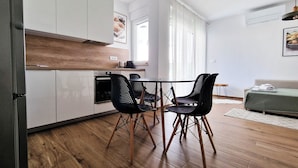 Eine moderne Küche mit weißen Schränken, einer Holz Arbeitsplatte und einem Essbereich mit schwarzen Stühlen.