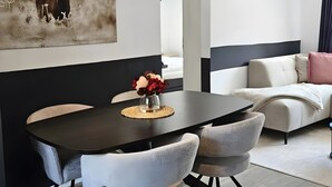 Un comedor moderno con una mesa negra, sillas blancas y una lámpara fijada a la pared.